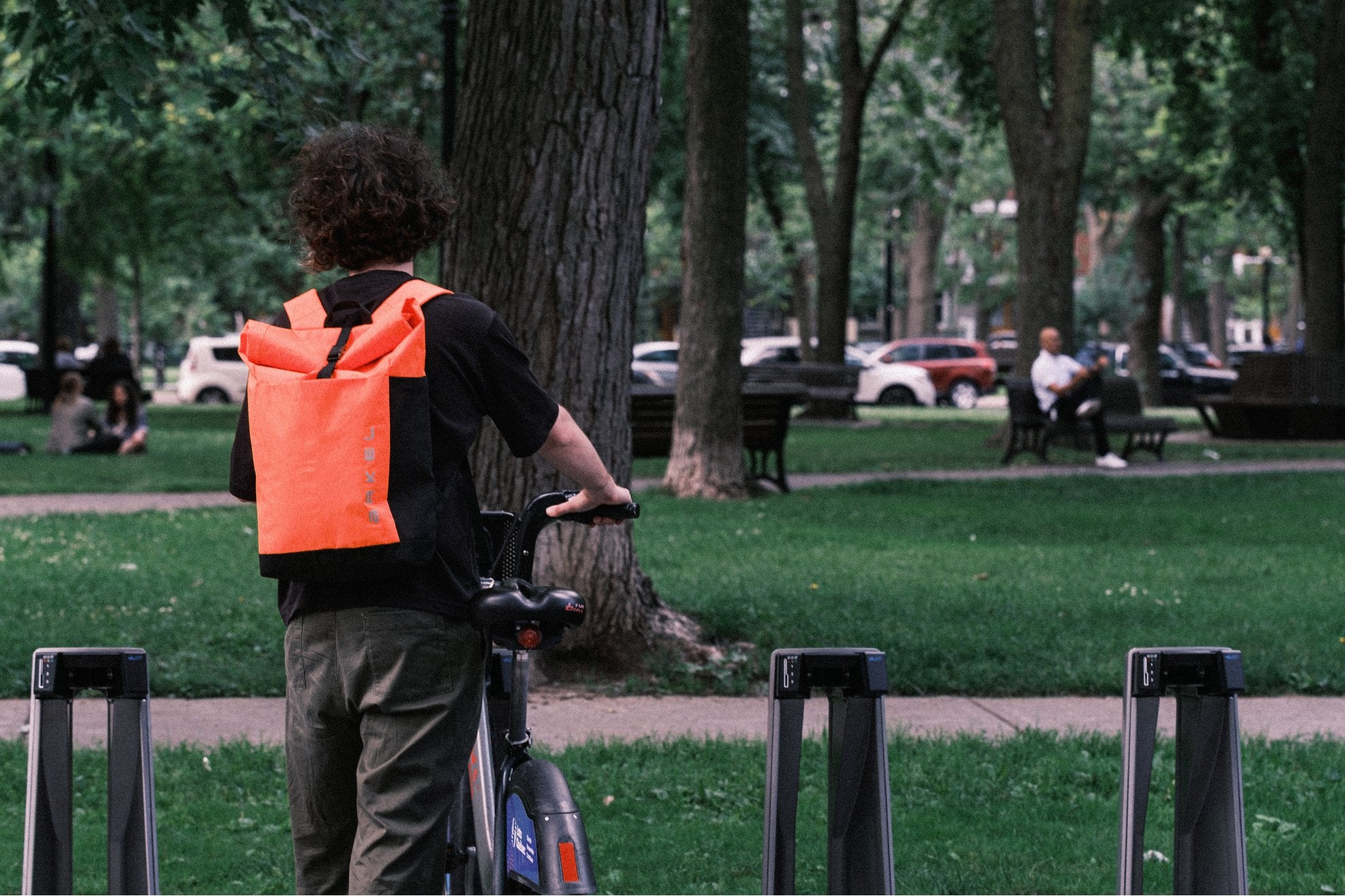 Man with orange backpack riding a bike