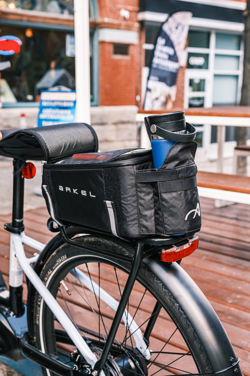 Bicycle with a black bag labeled 'Arkel' on a wooden deck.