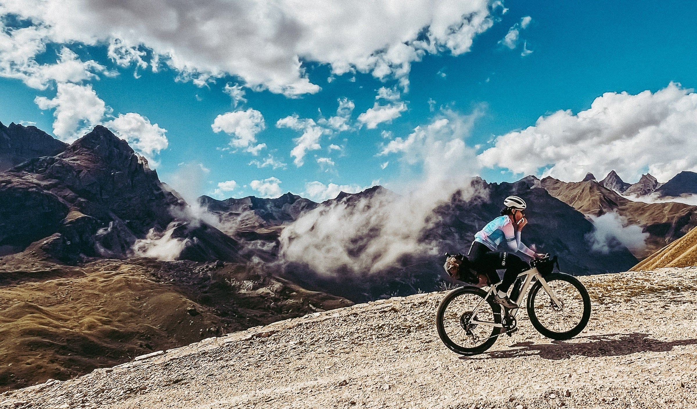 Person on a bicycle in a mountainous landscape with a clear blue sky.